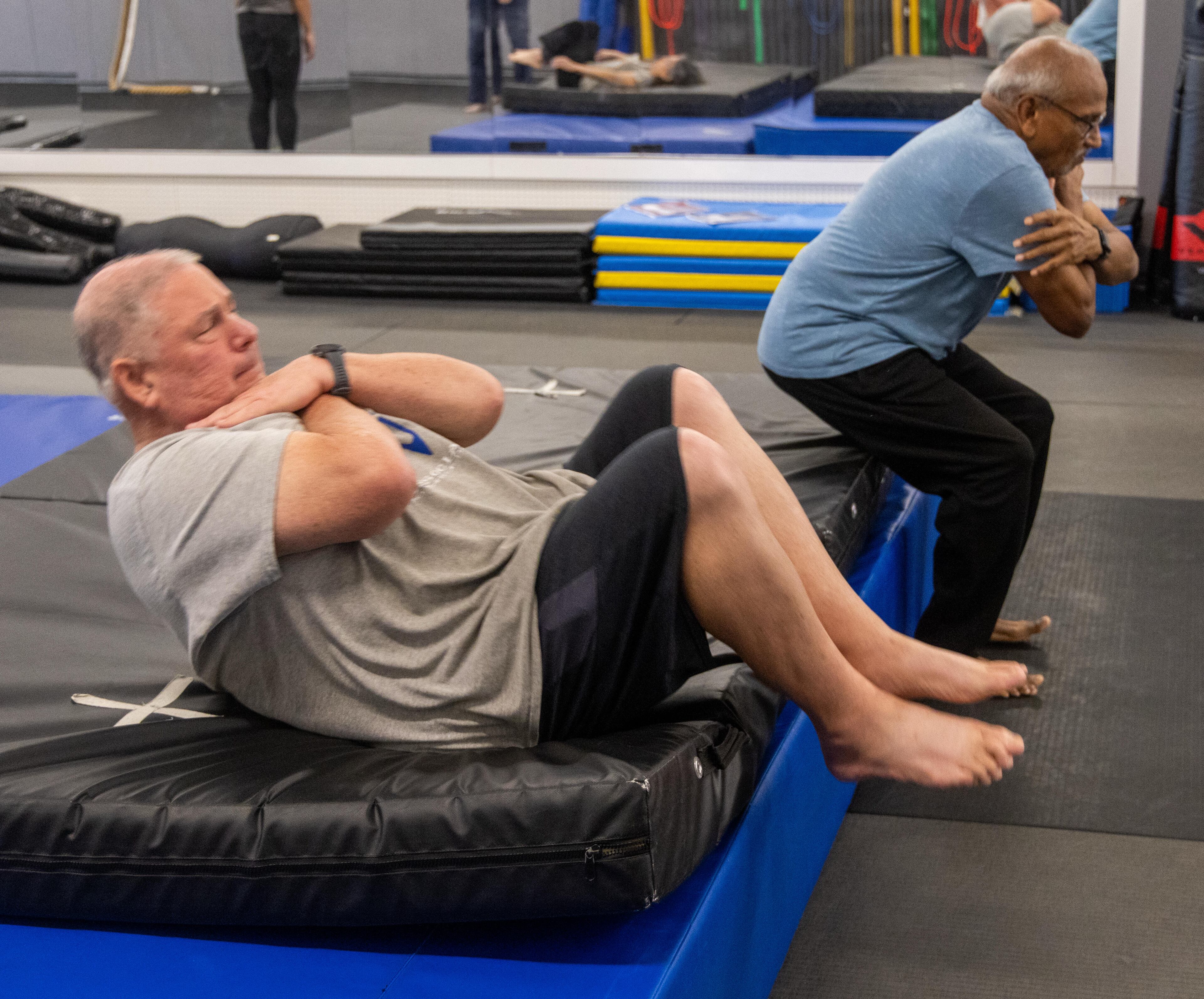 Jim Tebbel (left) and Shankaran Mahadevan practice falling backward safely at Atlanta Judo Midtown. (Phil Skinner for the AJC)