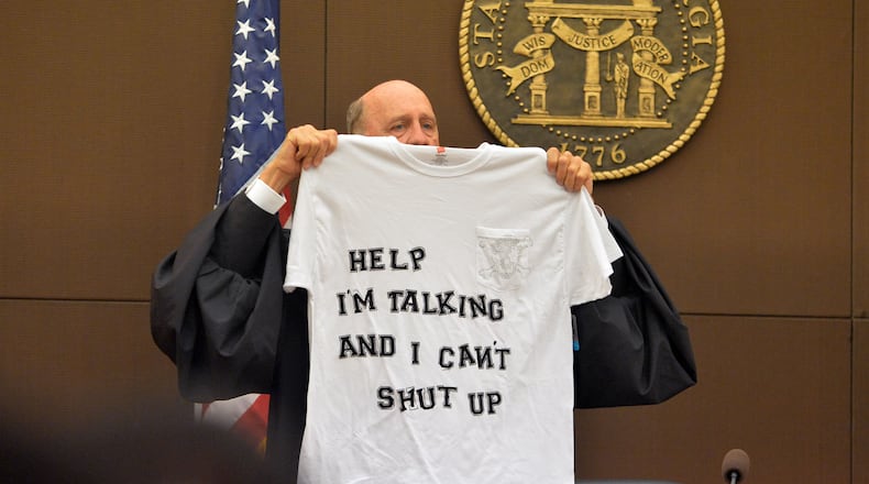 Judge Jerry Baxter holds up a T-shirt he bought for a "dubious achievement award" that he hopes not to give out during the course of the trial. The prosecution laid out its case to kick off the Atlanta Public Schools test-cheating trialin Fulton County Superior Court, Monday on Sept. 29, 2014. Not all 12 defense lawyers would make opening statements; some planned to reserve theirs until after the prosecution presented its case. KENT D. JOHNSON / KDJOHNSON@AJC.COM