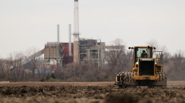 A worker prepares a plot of land for an AI data center, with a retired power plant being refurbished to provide electricity for the facility in the distance, March 24, 2026, in Independence, Mo. (Charlie Riedel/AP)