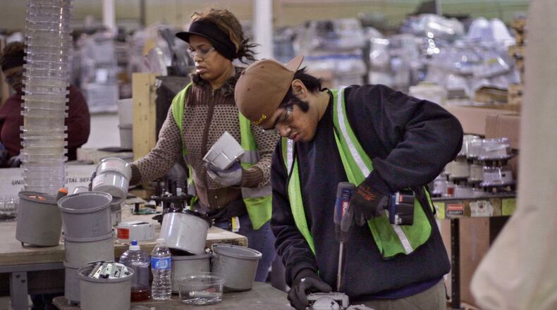 Tracey Lyons (left) and Christopher Napisa disassemble old Georgia Power electric meters at the Tommy Nobis Center. The vests indicate they are hearing impaired.