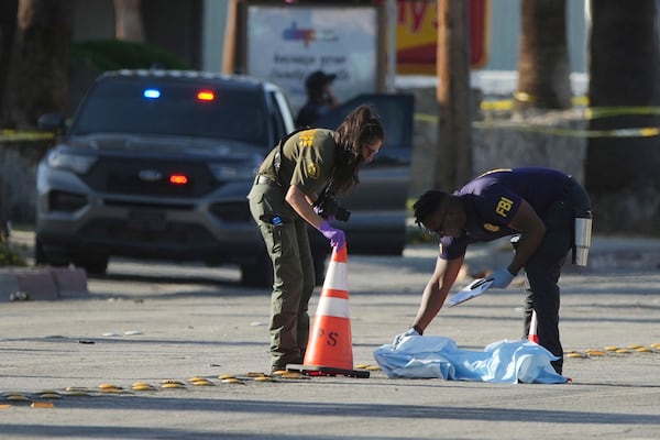 Investigators place a tarp over an item on a road near the site of an explosion in Palm Springs, Calif., on Saturday, May 17, 2025. (AP Photo/Eric Thayer)