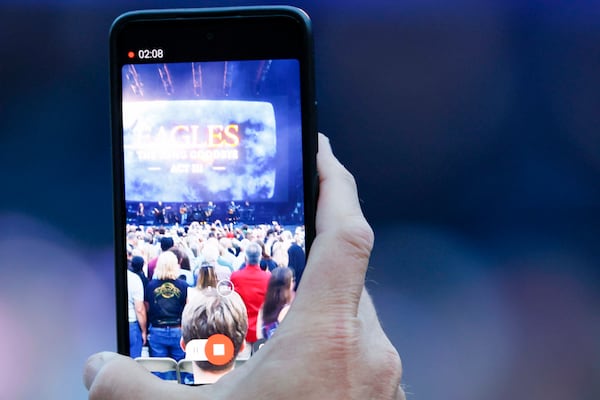 A fan films a video as the Eagles take the stage during the Long Goodbye Act III tour at Truist Park on Tuesday, May 5, 2026.  (Miguel Martinez/AJC)