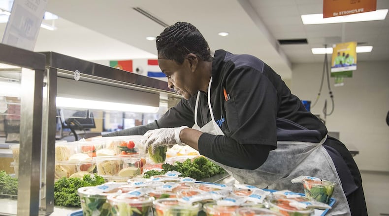 Kitchen food service worker Lola Thomas sets out salads for students in the cafeteria at Heards Ferry Elementary School in Sandy Springs. Local nonprofit All for Lunch paid off student lunch debt at hundreds of schools across metro Atlanta. (Alyssa Pointer / AJC file photo)