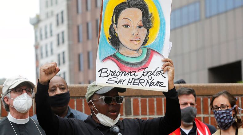 Kevin Peterson, founder and executive director of the New Democracy Coalition, displays a placard showing Breonna Taylor as he addresses a rally in Boston.