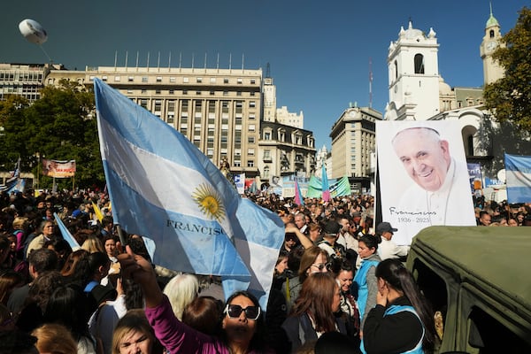 A mourner holds an Argentine flag as she pays tribute to the late Pope Francis outside the Cathedral in Buenos Aires, Argentina, Saturday, April 26, 2025, on the day of his funeral in Rome. (AP Photo/Victor R. Caivano)