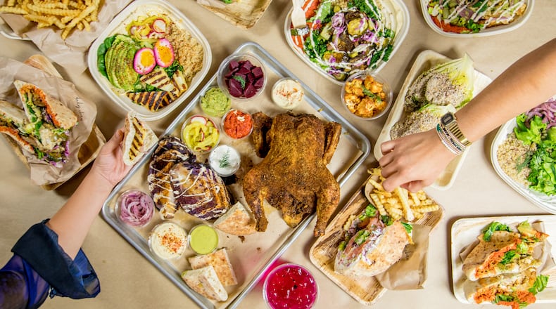 Selection of Daily Chew menu items including pitas, veggie-filled bowls, rotisserie chicken and cabbage plate, crunchy fries, daily housemade juice, and little gem wedge salad. / Photo by Kate Blohm