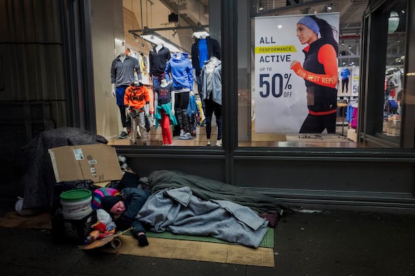 FILE - A homeless person sleeps under a blanket outside an Old Navy store window display in New York, Jan. 11, 2017. (AP Photo/Mark Lennihan, File)