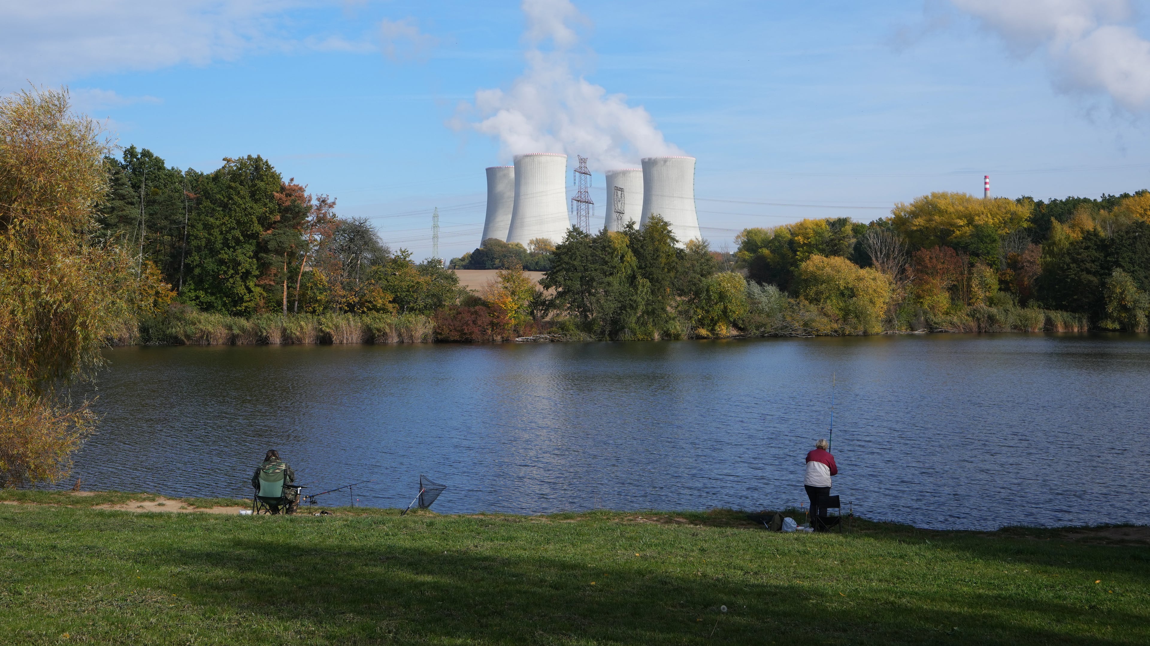 People fish near the towering Dukovany nuclear power plant, background, in Dukovany, Czech Republic, Oct. 21, 2025. (AP Photo/Petr David Josek)