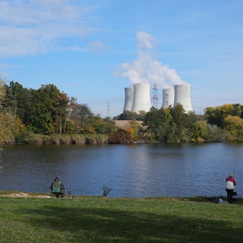 People fish near the towering Dukovany nuclear power plant, background, in Dukovany, Czech Republic, Oct. 21, 2025. (AP Photo/Petr David Josek)