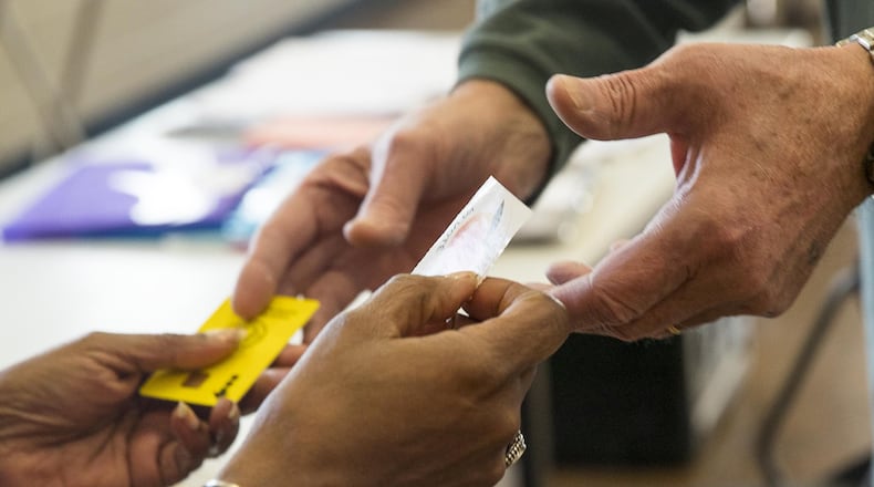 A Gwinnett County poll worker hands a voter a sticker after casting their ballot during the Gwinnett County MARTA referendum special election at the Mountain Park Aquatic Center and Activity Building in Lilburn on March 19, 2019. (ALYSSA POINTER/ALYSSA.POINTER@AJC.COM)