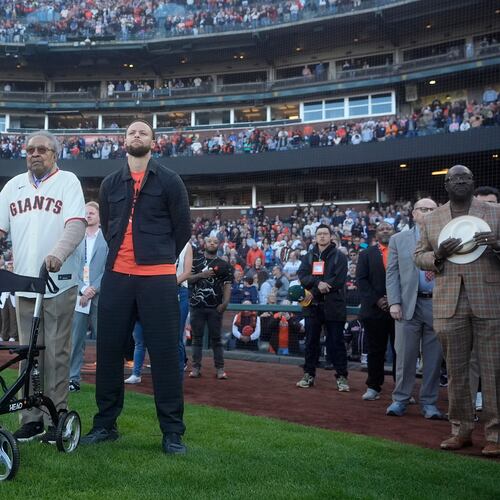 FILE - Dr. Clarence B. Jones, left, a former speech writer for Martin Luther King Jr., stands next to Golden State Warriors basketball player Stephen Curry, front right, during the playing of Lift Every Voice and Sing before a baseball game between the San Francisco Giants and the New York Yankees in San Francisco, May 31, 2024. (AP Photo/Jeff Chiu, File)