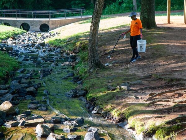 Karen Edwards uses a grabber to pick up a bottle as she works a group of his neighbors picking up trash at Hairston Park in Stone Mountain. PHIL SKINNER FOR THE ATLANTA JOURNAL-CONSTITUTION.