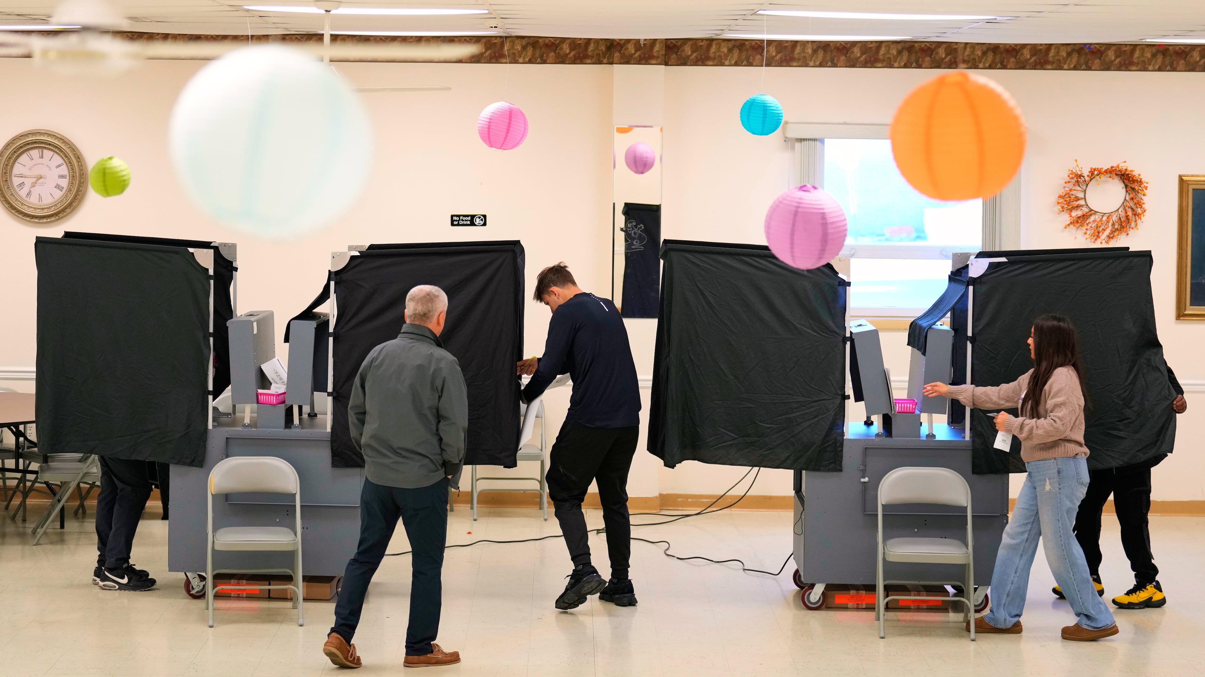 Poll workers help people get set up to vote at a polling site in Garfield, N.J., Tuesday, Nov. 4, 2025. (AP Photo/Seth Wenig)