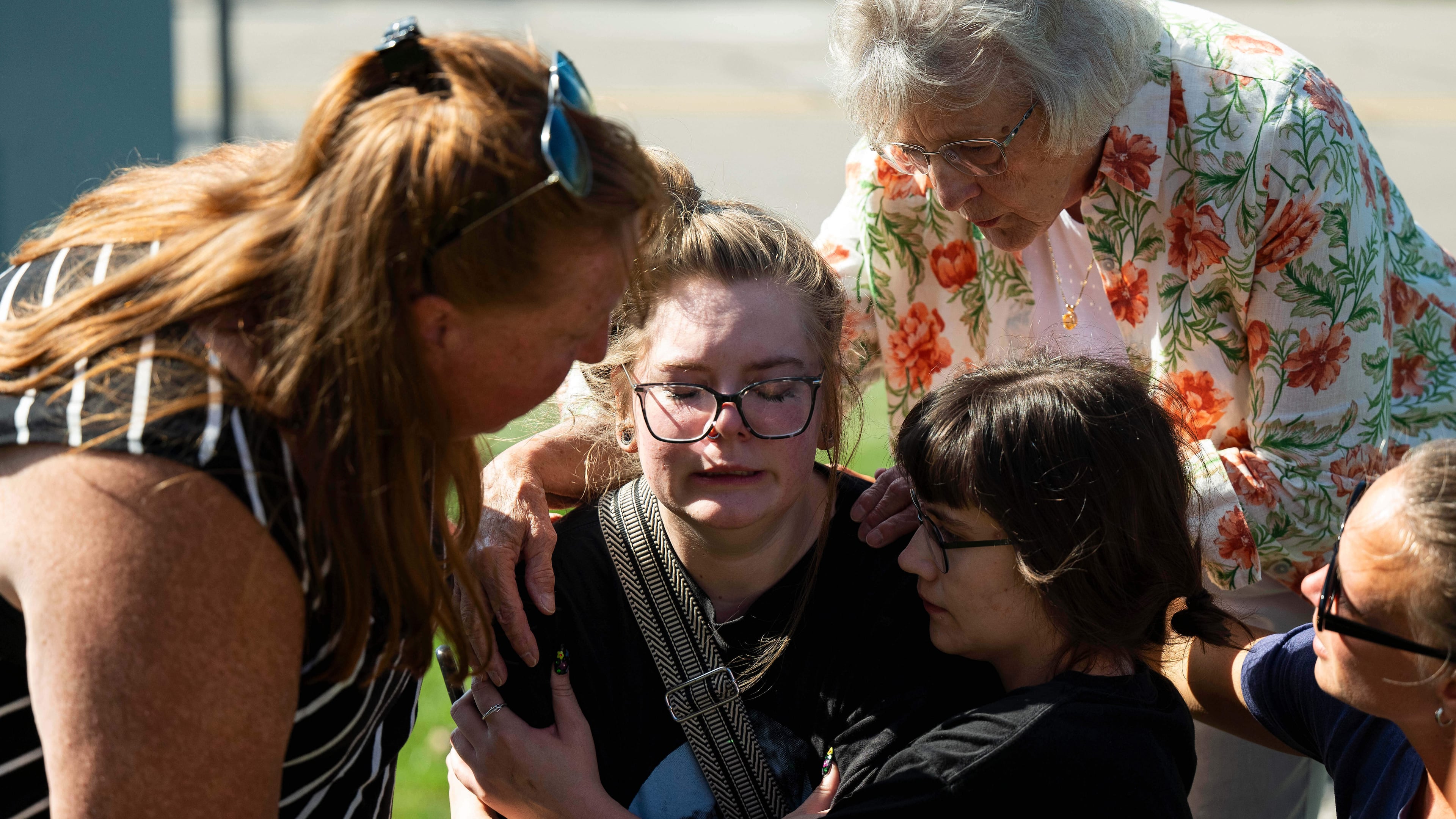 Joanne Green of Fenton, 75, top right, and McKenna Harrington of Davison, 25, second from right, comfort Katelyn Kruse of Fenton, 26, center, after Kruse was present at the scene of a shooting and structure fire at The Church of Jesus Christ of Latter-day Saints on McCandlish Road in Grand Blanc, Mich., Sunday, Sept. 28, 2025. (Katy Kildee/Detroit News via AP)