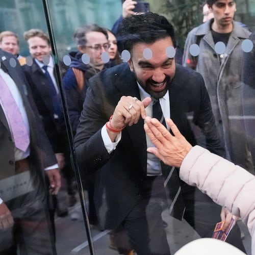 New York City mayoral candidate Zohran Mamdani waves to Rita Bellevue as she waits at a bus stop in New York, Monday, Oct. 27, 2025. (AP Photo/Seth Wenig)