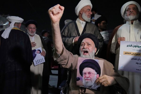 An Iraqi Shiite cleric holds a portrait of Iran's Supreme Leader Ayatollah Ali Khamenei during a protest against Israeli attacks on multiple cities across Iran, at a bridge leading to the fortified Green Zone where the U.S. Embassy is located in Baghdad, Iraq, Thursday, June 19, 2025. (AP Photo/Hadi Mizban)