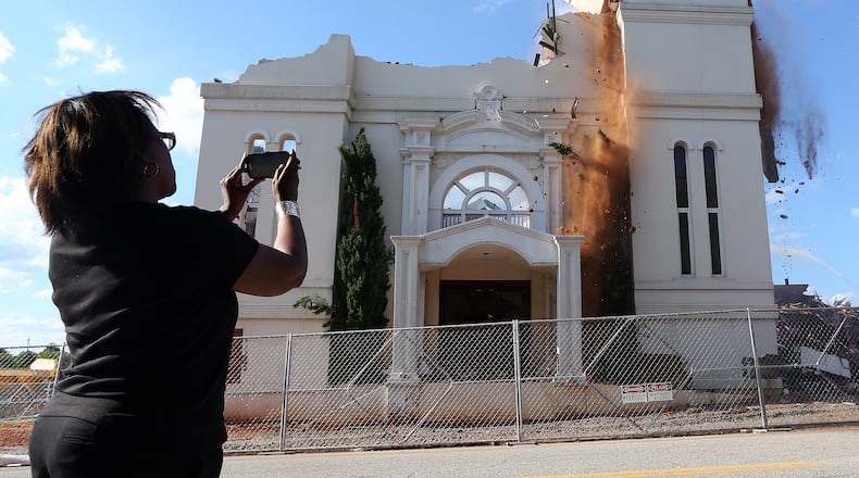 Alvelyn Sanders uses her phone to take photographs as the facade of Friendship Baptist Church is knocked down Monday evening July 28, 2014 to make way for the new Falcons’ stadium. BEN GRAY / AJ FILE PHOTO