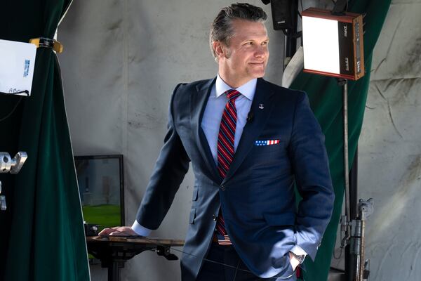 Wearing a U.S. flag themed pocket square and belt buckle, Defense Secretary Pete Hegseth waits for the start of a television interview outside the White House, Friday, March 21, 2025, in Washington. (AP Photo/Jacquelyn Martin)
