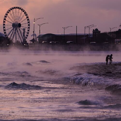 People walk on an ice covered beach along the shore of Lake Michigan, Friday, Jan. 23, 2026, in Chicago. (AP Photo/Kiichiro Sato)