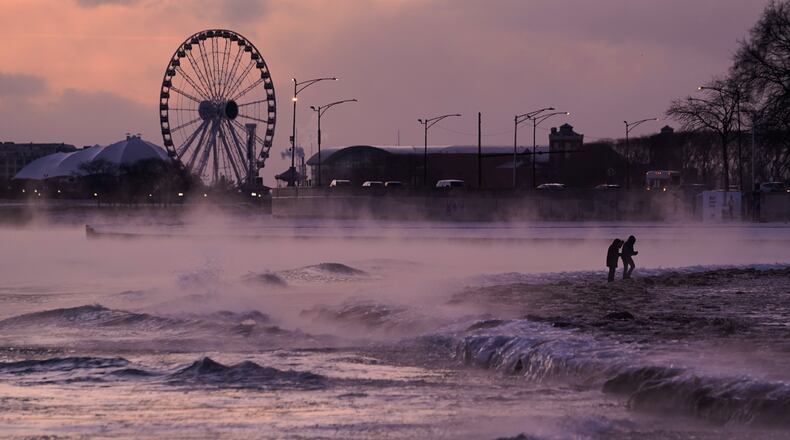 People walk on an ice covered beach along the shore of Lake Michigan, Friday, Jan. 23, 2026, in Chicago. (AP Photo/Kiichiro Sato)