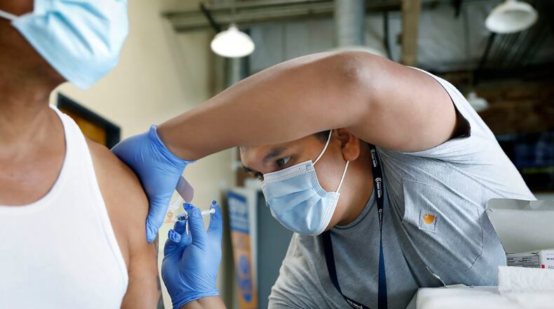 In this file photo, Jeremy Oyague, right, a registered nurse with The Los Angeles Department of Public Health, administers a COVID booster at a vaccination clinic to immunize people against monkeypox and COVID at The Village Mental Health Services in Los Angeles, a site run by The People Concern. (Christina House/Los Angeles Times/TNS)