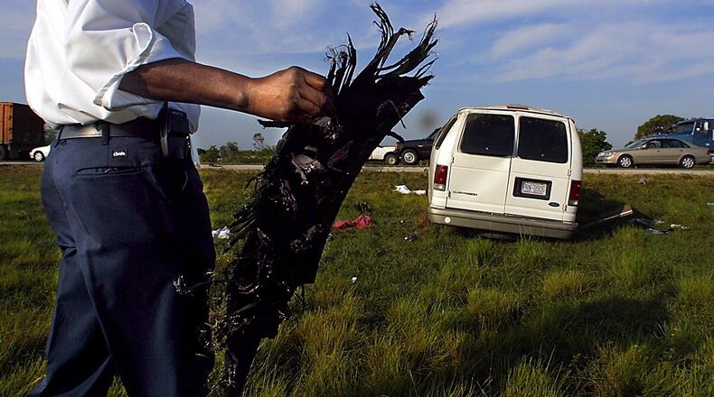 Road Ranger driver Eugene Smith picks up a large part of a tire from the median of I-95 at the 92 mile marker, three miles south of Hobe Sound, after a Ford Clubwagon loaded with 15 migrant workers blew its right rear tire and rolled over Tuesday, April 2, 2002. Although numerous occupants were ejected from the vehicle, none sustained life-threatening injuries. Staff photo by Chris Matula
