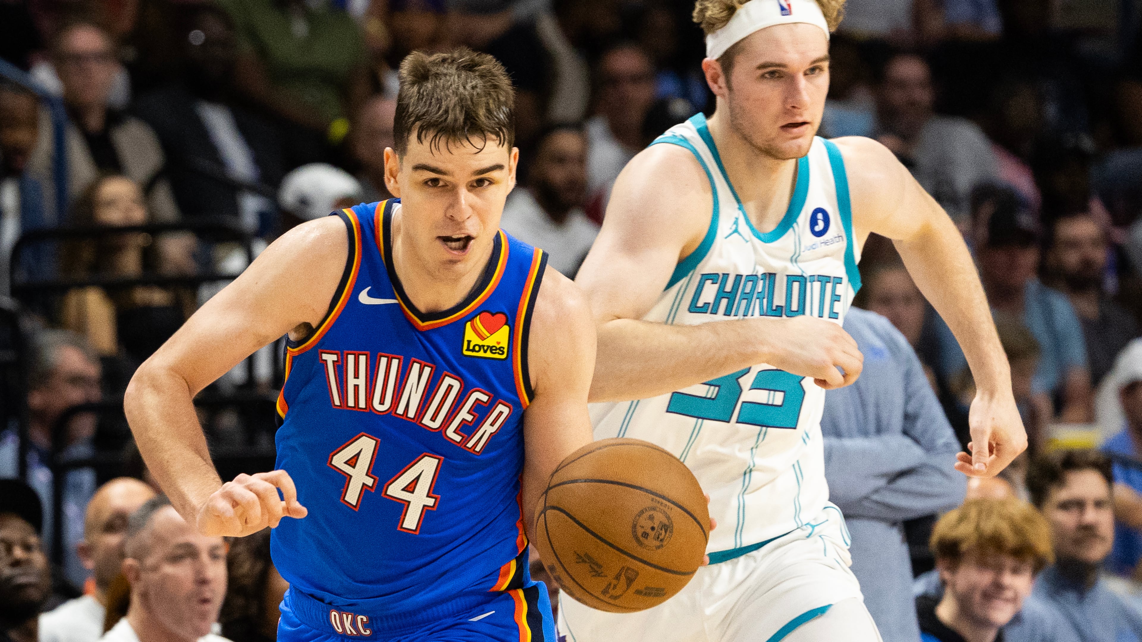 Oklahoma City Thunder guard Nikola Topic, left, drives the ball upcourt against Charlotte Hornets forward Liam McNeeley, right, during the second half of an NBA basketball preseason game in North Charleston, S.C., Sunday, Oct. 5, 2025. (AP Photo/Mic Smith)