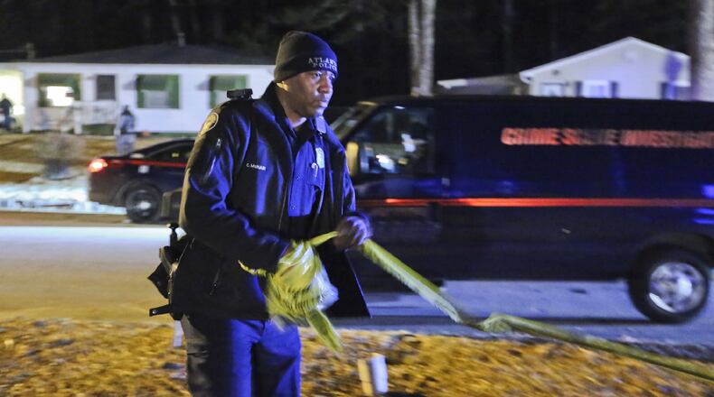 An Atlanta police officer gathers crime scene tape after the shooting investigation of a man found dead inside a vehicle last February. Photo by John Spink /AJC