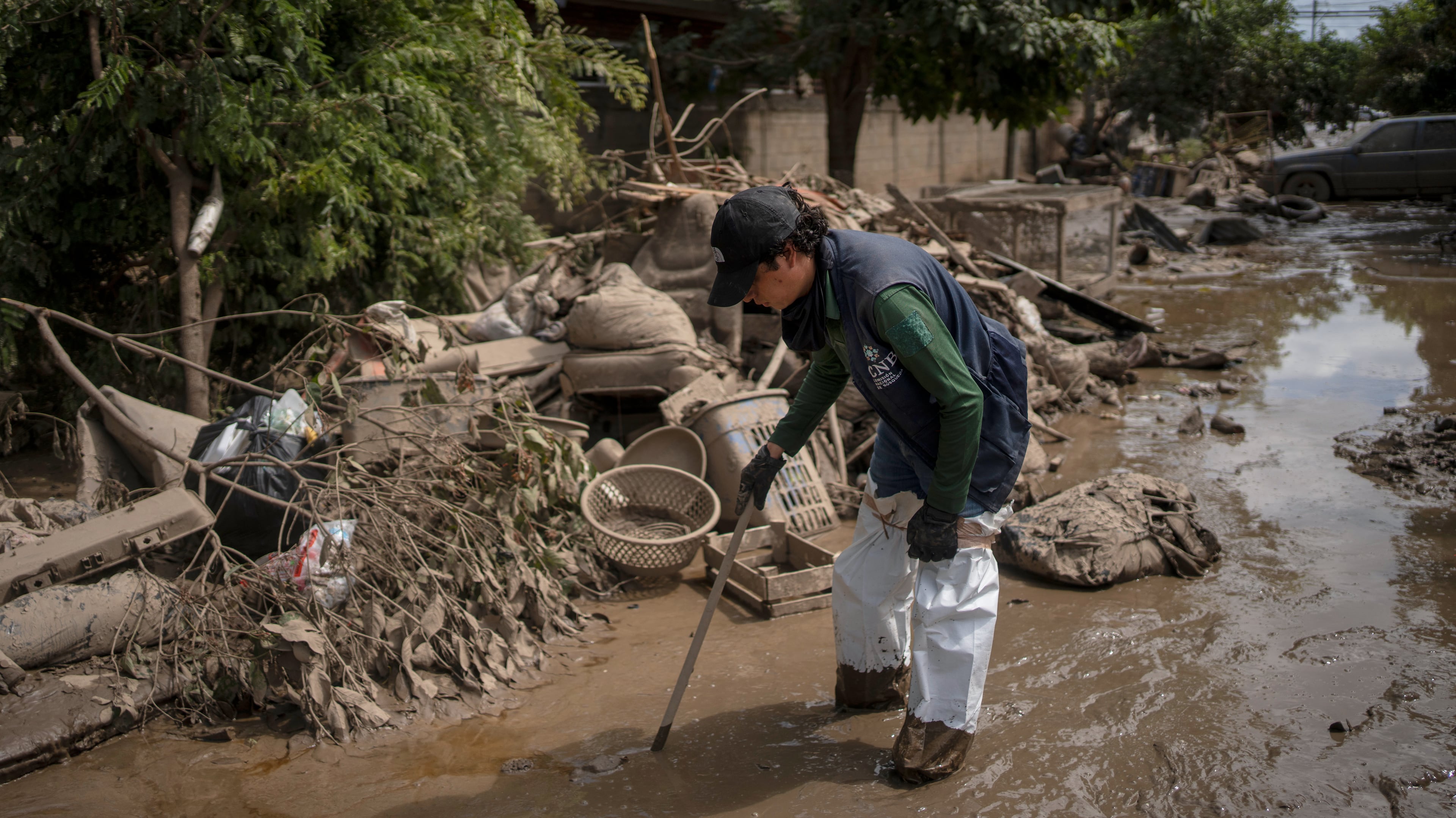 A public official searches for missing people on a mud-covered street in Poza Rica, Veracruz state, Mexico, on Tuesday, Oct. 14, 2025, after landslides and torrential rain. (AP Photo/Felix Marquez)
