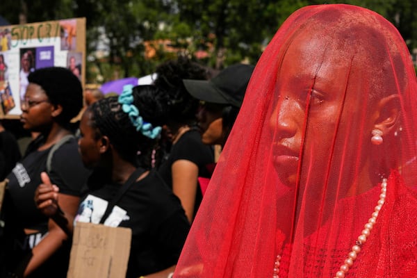 Activist Karabo Khumo dressed in red dress cover-up in a veil as "Lady Justice" during the women's protest and hand over of a petition demanding that gender-based violence and femicide be declared a national disaster, at the Union Buildings in Pretoria, South Africa, Friday, April 11, 2025. (AP Photo/Themba Hadebe)