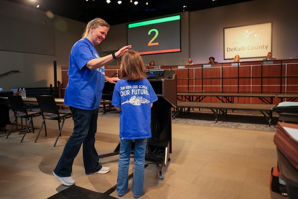 Ginny Fairchild, left, congratulates her 7-year-old daughter, Emily, a first grade student at Oak Grove Elementary, after Emily spoke to the DeKalb County School Board during the public comment portion of a board meeting on Monday, April 20, 2026, in Stone Mountain. Oak Grove is one of the schools proposed for closure. (Jason Getz/AJC)