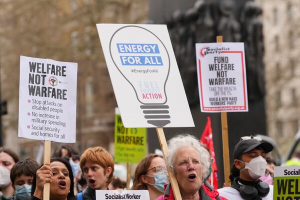 Protesters show placards as Britain's Chancellor Rachel Reeves is about to leave 11 Downing Street to deliver the spring statement in London, Wednesday, March 26, 2025. (AP Photo/Kirsty Wigglesworth)