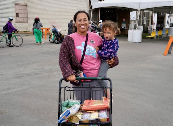 Alameda resident Christina Santamaria stands outside the Alameda Food Bank with groceries and her daughter in Alameda, Calif. on Friday, April 25, 2025. (AP Photo/Terry Chea)