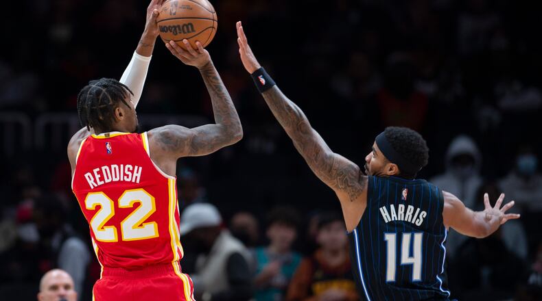 Hawks forward Cam Reddish shoots as Orlando guard Gary Harris defends during the first half of a NBA basketball game Wednesday, Dec. 22, 2021, in Atlanta. (AP Photo/Hakim Wright Sr.)
