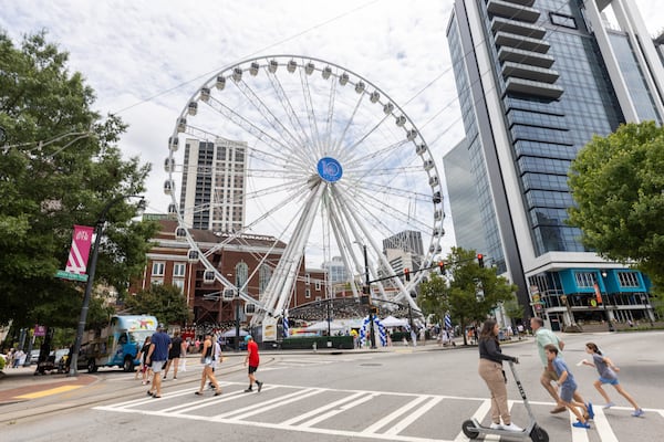 People cross Centennial Olympic Park Drive in front of the SkyView, a 20-story Ferris wheel in Atlanta. (Steve Schaefer/AJC 2023)