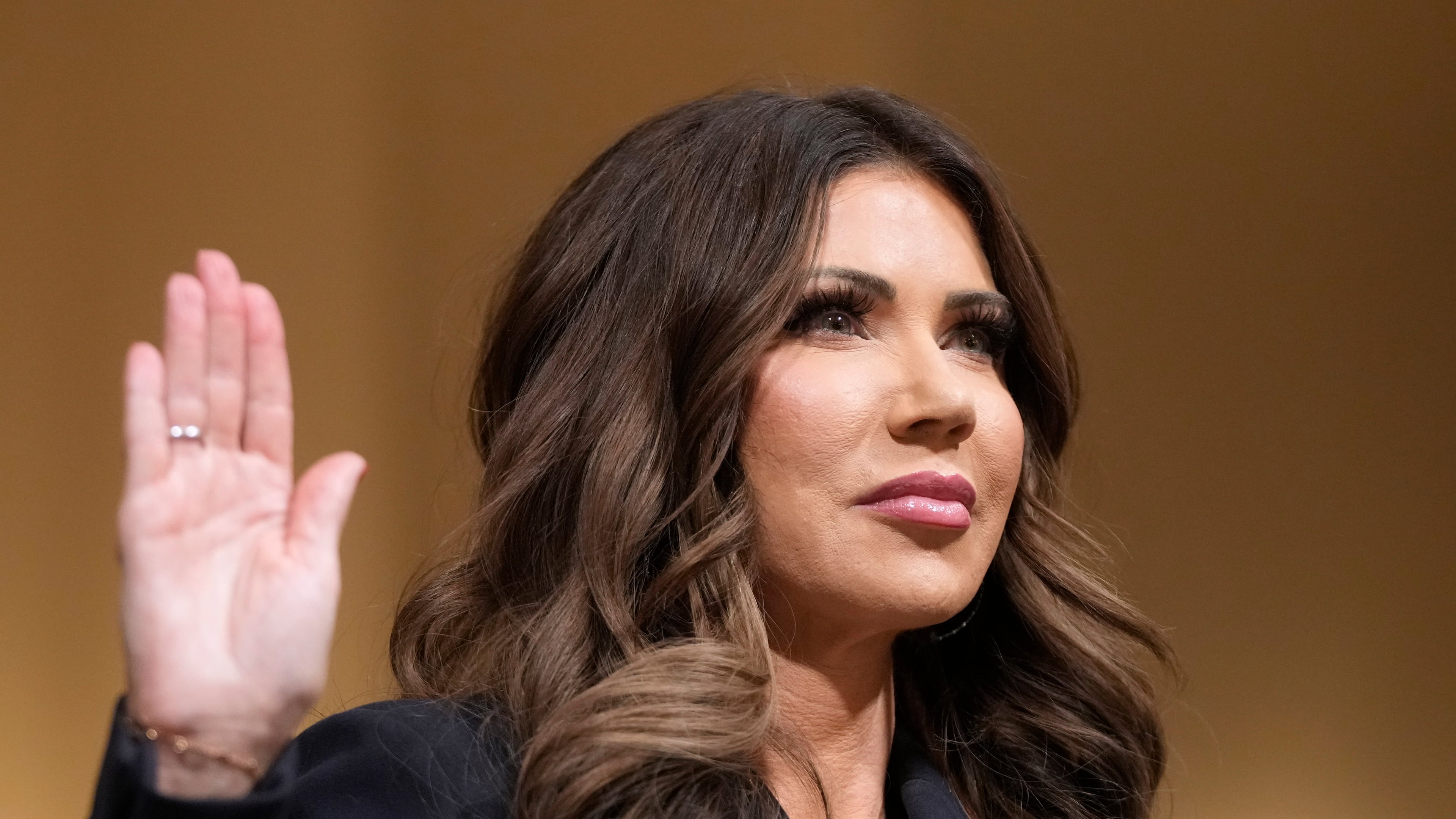 Homeland Security Secretary Kristi Noem raise her arm before the House Committee on Homeland Security on Capitol Hill in Washington, Thursday, Dec. 11, 2025. (AP Photo/Mark Schiefelbein)