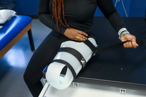 DeKalb County firefighter Eboni Kennedy puts on a protective leg covering during her physical therapy at the Shepherd Center. (Jason Getz/AJC)