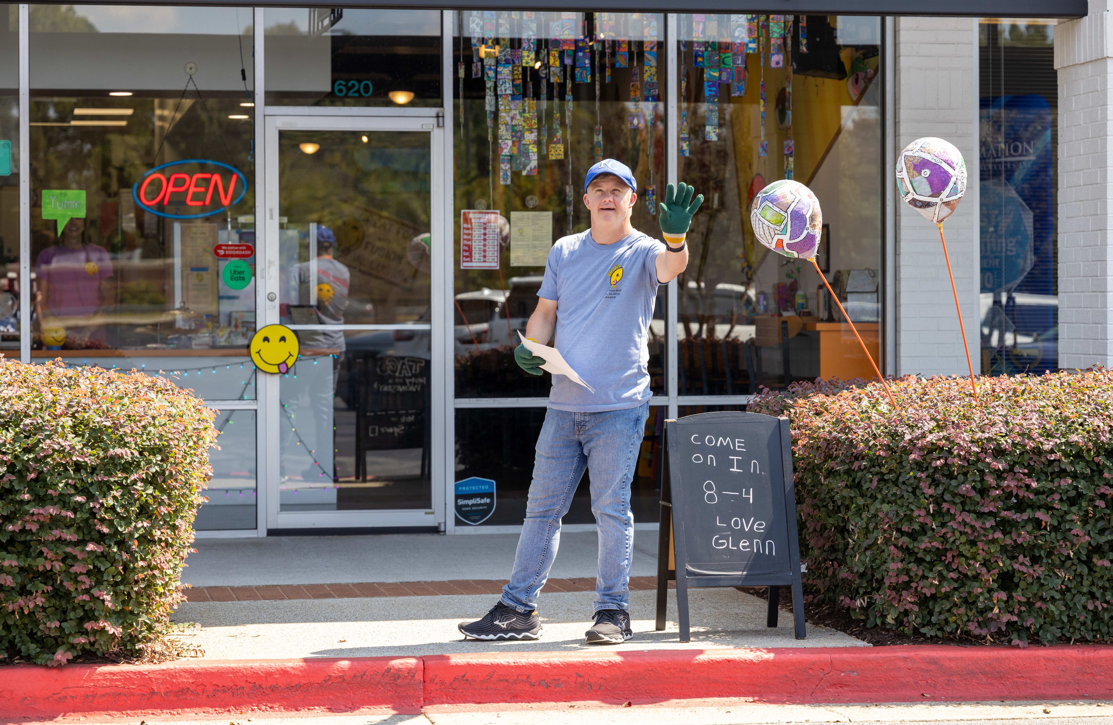 As guest relations specialist, Glenn Hutchinson waves to passerby in front of Glenn's Cafe in Mableton. (Phil Skinner of the AJC)