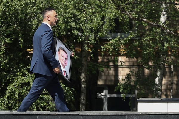 A man carries a portrait of Roman Starovoit, the former transport minister who died in an apparent suicide after his dismissal while people line up to his bid farewell, at the morgue of the Central Clinical Hospital in Moscow, Russia, Thursday, July 10, 2025. (AP Photo)