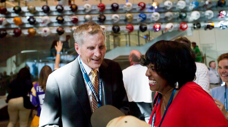 Former Georgia Tech, Alabama, Kentucky and Georgia State football coach, Bill Curry, left, greets visitors at the College Football Hall of Fame grand opening, Saturday, Aug. 23, 2014, in Atlanta. The new high-tech hall features an interactive experience that begins when the guest registers for a smart pass, selects a favorite school and then sees that school's helmet illuminated. (AP Photo/David Goldman)
