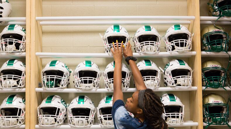 Natalee Bryant, 16, a football manager and rising junior, places helmets in a rack at Buford High School in Buford, Ga., on Thursday, July 18, 2019. Classes will begin at the, 214,000 square foot school on August 7. (Casey Sykes for The Atlanta Journal-Constitution)