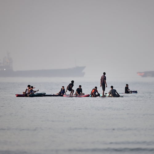 People gather on paddleboards in shallow water as cargo and service vessels are anchored in the Strait of Hormuz off Bandar Abbas, Iran, Monday, June 1, 2026. (Amirhosein Khorgooi/ISNA via AP)