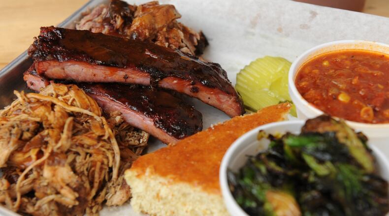 Combo plate with chicken, pulled pork and ribs, served with cornbread, fried Brussels sprouts and Brunswick stew at Lovies BBQ in Buckhead. (BECKY STEIN)