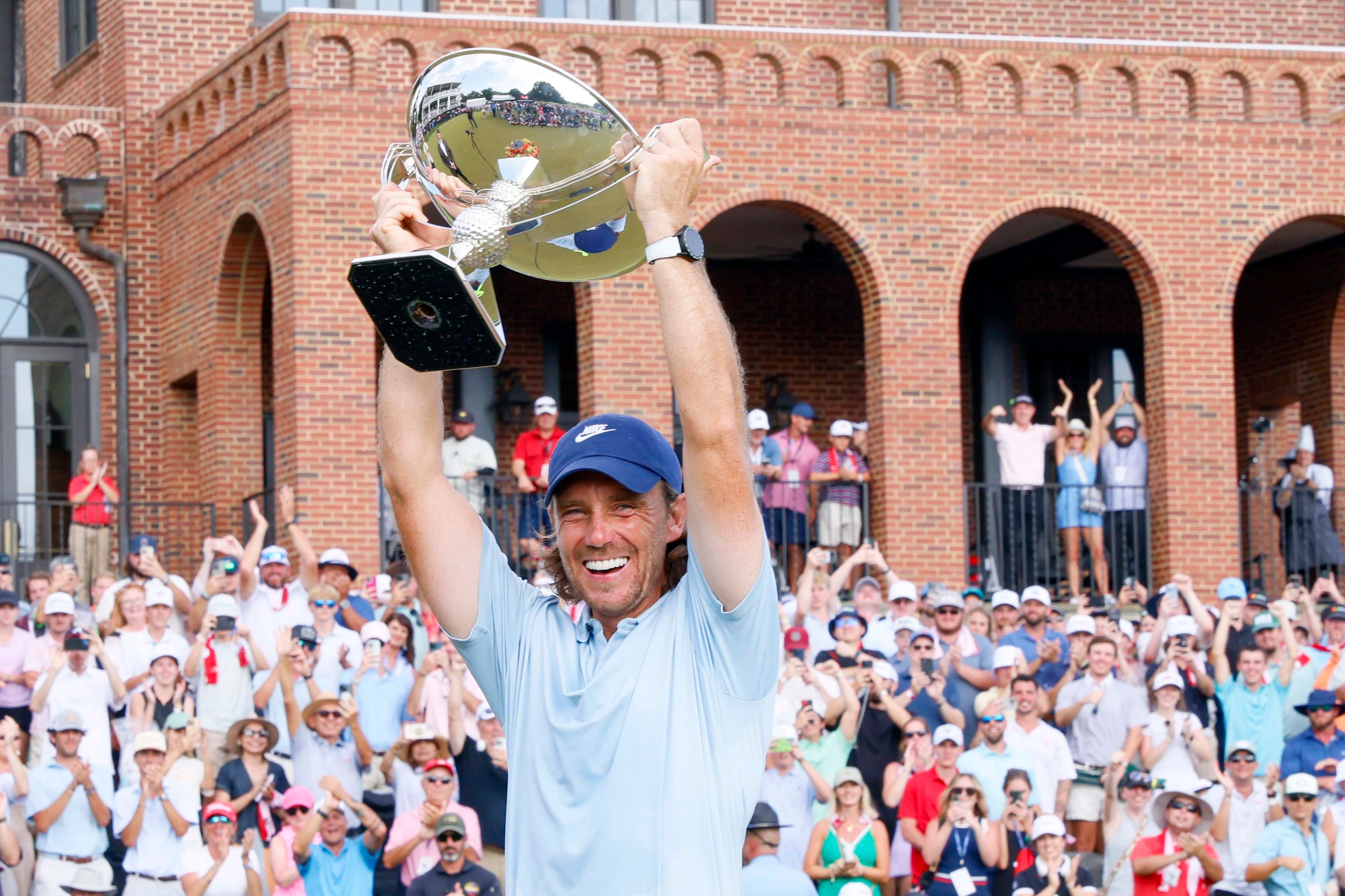 Tommy Fleetwood of England smiles as he lifts the PGA Tour Championship trophy at East Lake Golf Club on Sunday, Aug. 24, 2025, in Atlanta. (Miguel Martinez/ AJC)