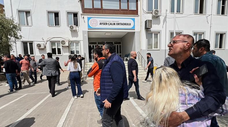 People stand at the courtyard of a secondary school where an assailant opened fire, in Kahramanmaras, Turkey, Wednesday, April 15, 2026, (IHA via AP)