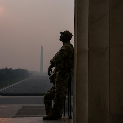 National Guardsmen patrol the Lincoln Memorial as the sun, obscured by wildfire smoke, rises above the Washington Monument and the Reflecting Pool, Friday, July 17, 2026, on the National Mall in Washington. (AP Photo/Julia Demaree Nikhinson)