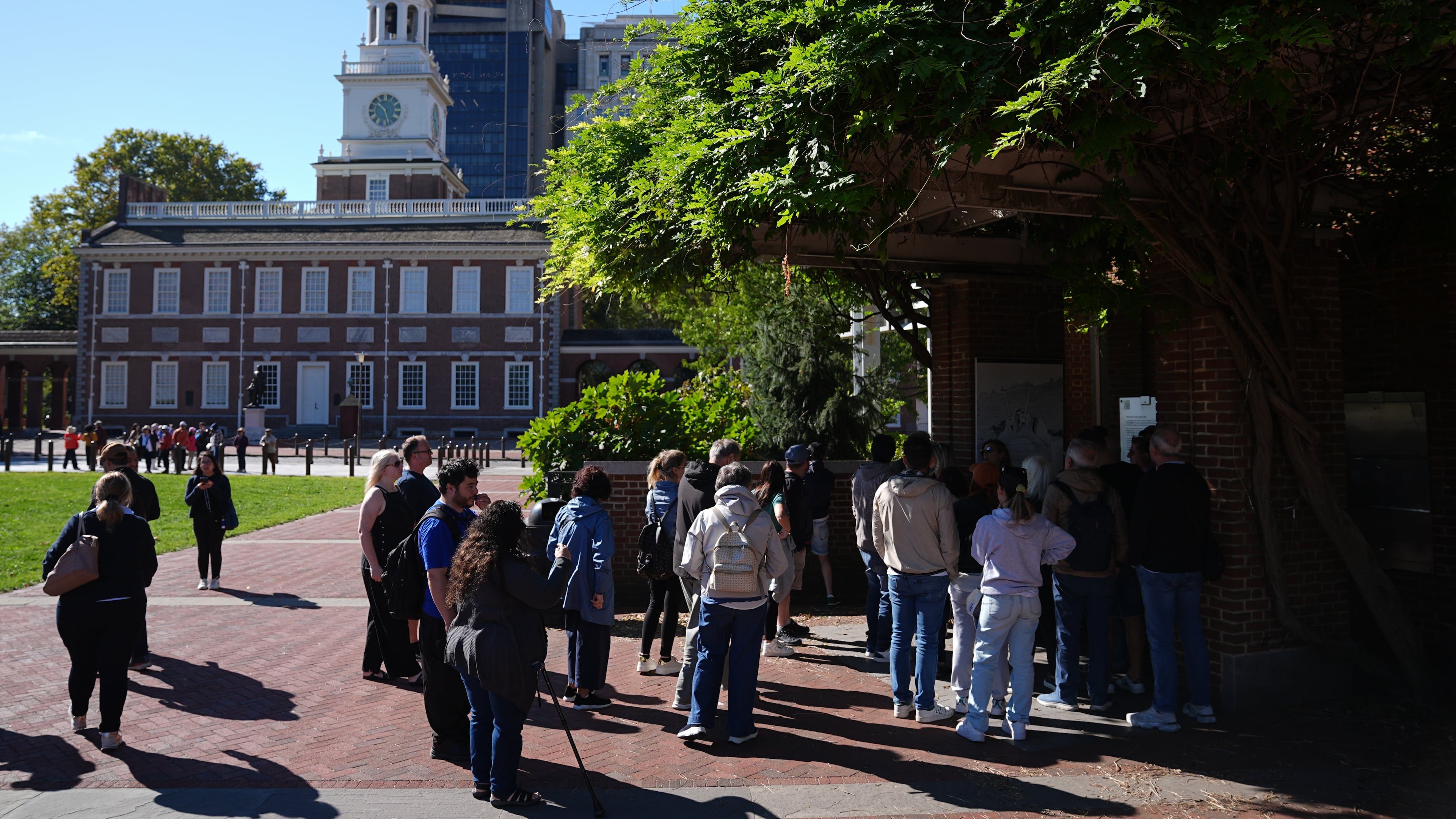 Tourist crowd around a window to view the Liberty Bell with Independence Hall in the background in Philadelphia, Wednesday, Oct. 1, 2025. (AP Photo/Matt Rourke)