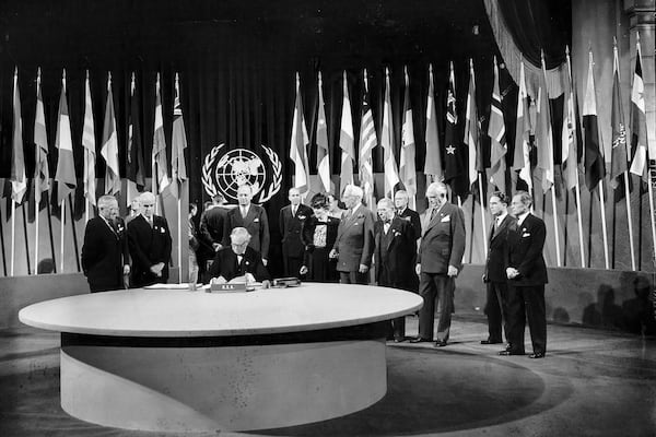 FILE - President Harry S. Truman and the entire American delegation watch as Sen. Tom Connally signs the United Nations Charter in San Francisco, June 26, 1945. Standing, from left: Truman; Secretary of State Edward Stettinius Jr.; Harold Edward Stassen; unidentified; Dean Virginia Gildersleeve; Rep. Charles A. Eaton; Rep. Sol Bloom, and Sen. Arthur Vandenberg. (AP Photo, File)