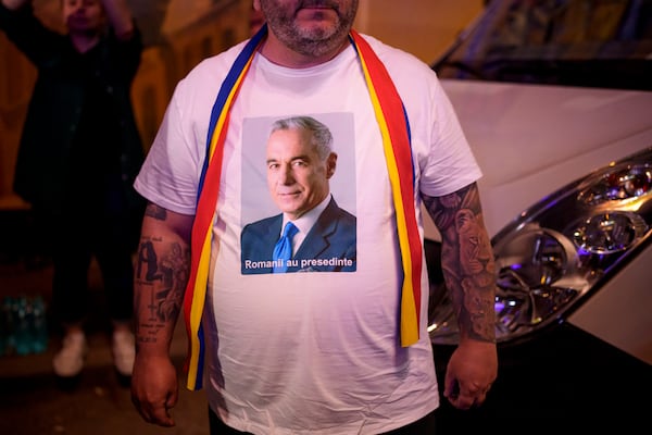A man wears a t-shirt showing Calin Georgescu, winner of the first round of last year's voided election outside the headquarters of presidential candidate George Simion, after polls closed during the first round of the country's presidential election redo in Bucharest, Romania, Sunday, May 4, 2025. (AP Photo/Andreea Alexandru)