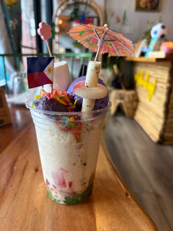 A cup of the Filipino dessert halo halo, made with layers of shaved ice, condensed milk and a variety of jellies, including coconut and palm, along with tapioca and mung beans, and topped with gummy candies and ube ice cream.